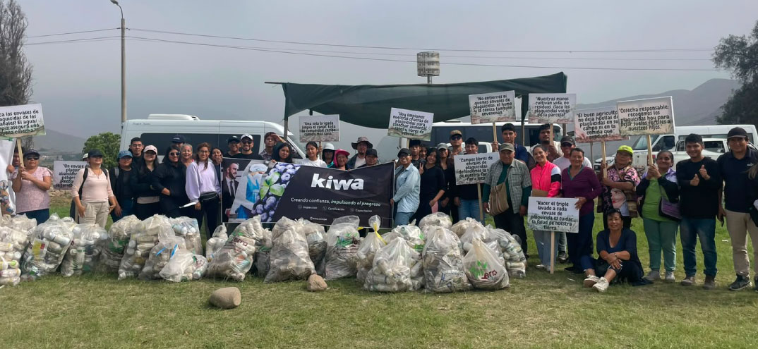 Grupo de personas posando al aire libre con pancartas y bolsas llenas de botellas plásticas recicladas, junto a una camioneta y un cartel de Kiwa.