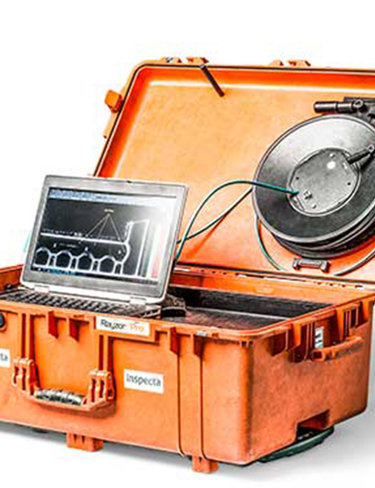Orange inspektionsv&auml;ska f&ouml;r DDA med &ouml;ppen lock, b&auml;rbar dator och rund industrikomponent med kablar.