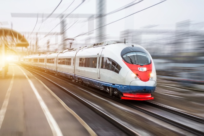 High-speed train traveling on railway tracks at sunset, showcasing modern transportation technology and rapid train travel.