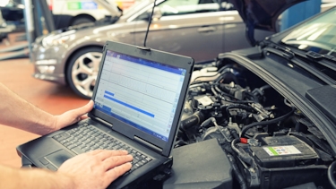 Bilmekaniker har kopplat in en dator till bilen för att hantera fordonsinformation.