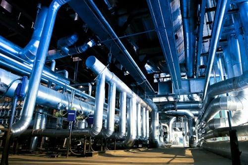 Ett rum fullt med olika slags rörledningar i en industri.