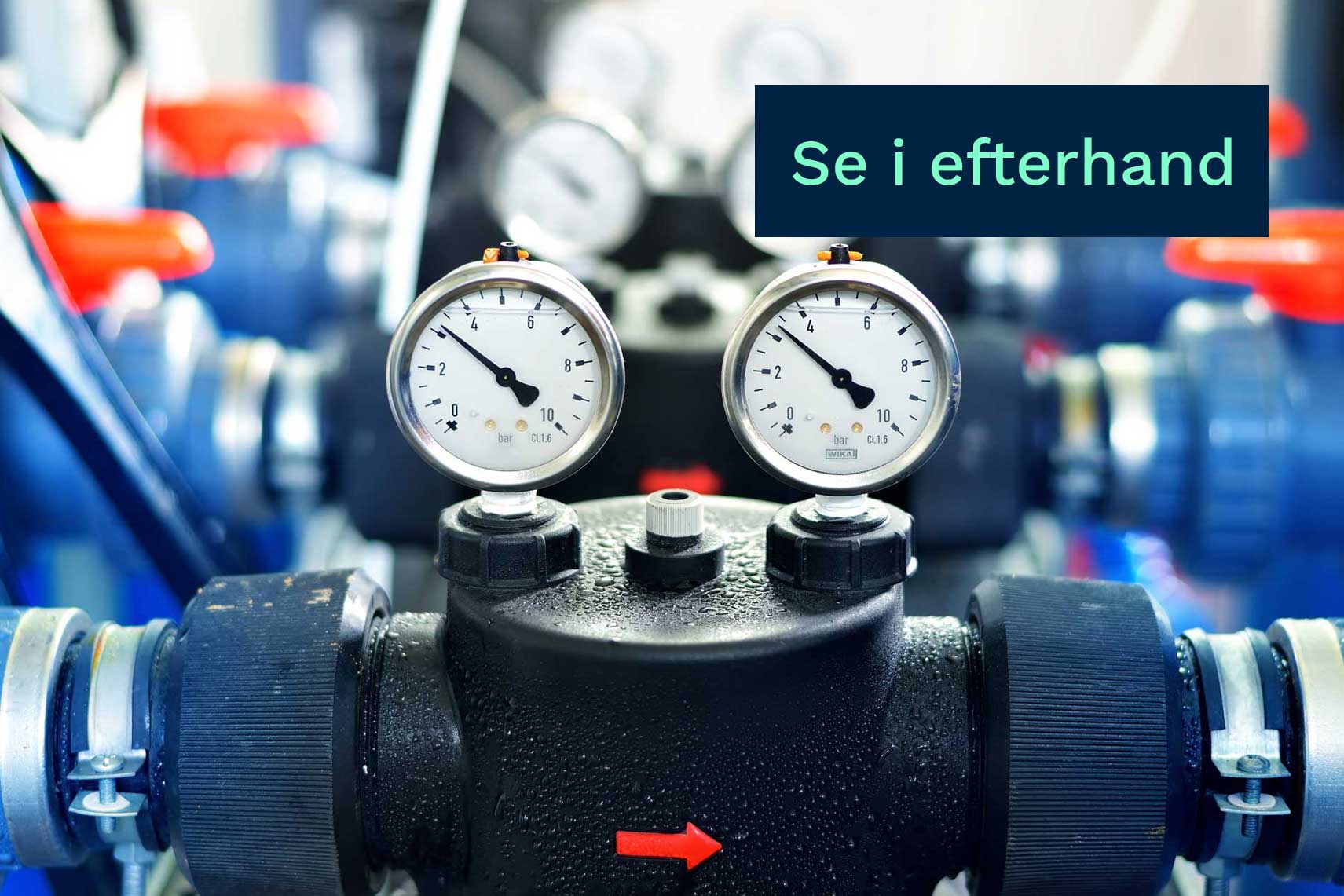 Närbild av två manometrar monterade på ett rörsystem, med en blå skylt som visar texten "se i efterhand".