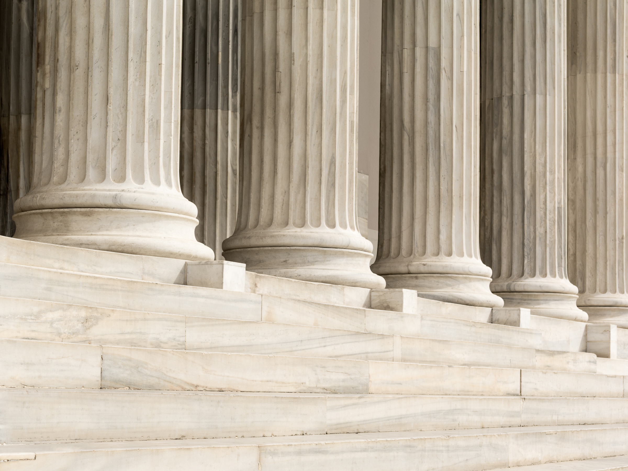 Marble columns of a neoclassical building with steps leading up to the structure.